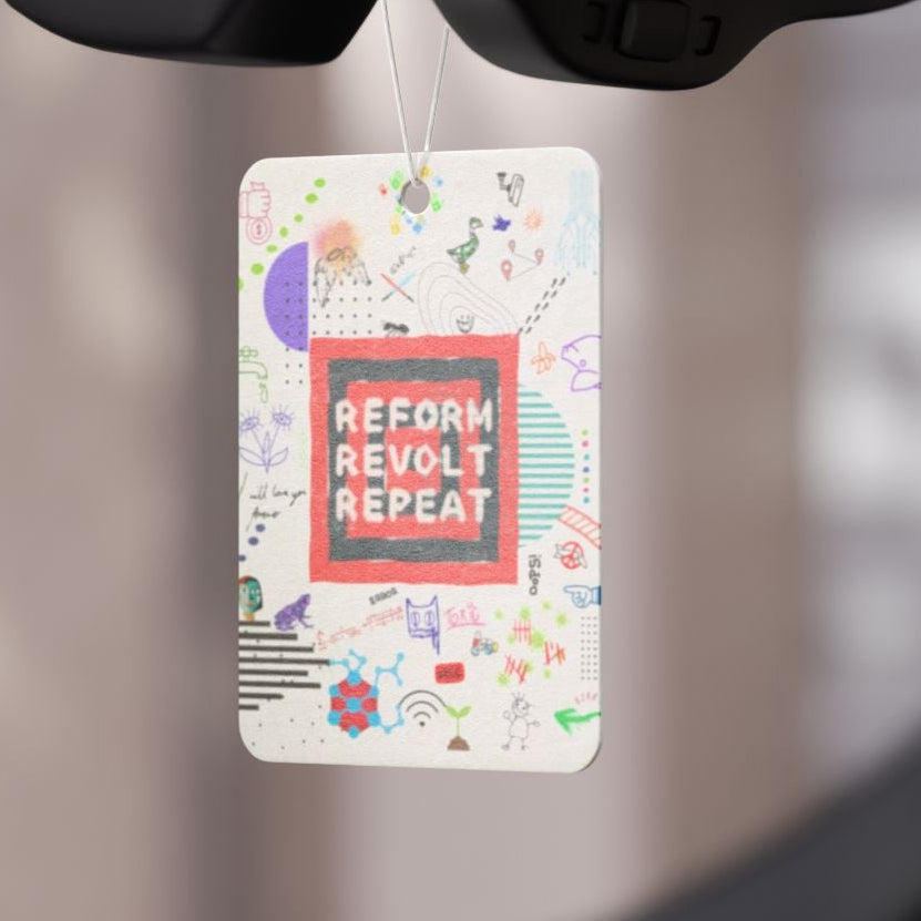 Car air freshener hanging from a car's rearview mirror with a blurred background.